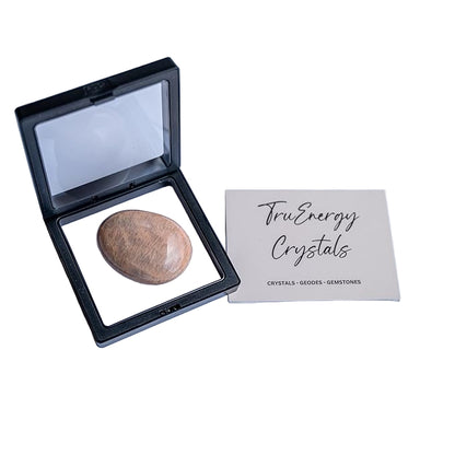 Open black crystal case with a stone inside on a white background, next to a 'TruEnergy Crystals' card.
